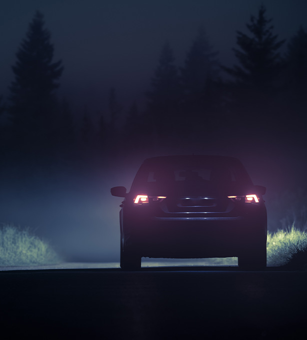 dark silhouette of a car on a foggy road with glowing tail lights atmospheric night drive experience